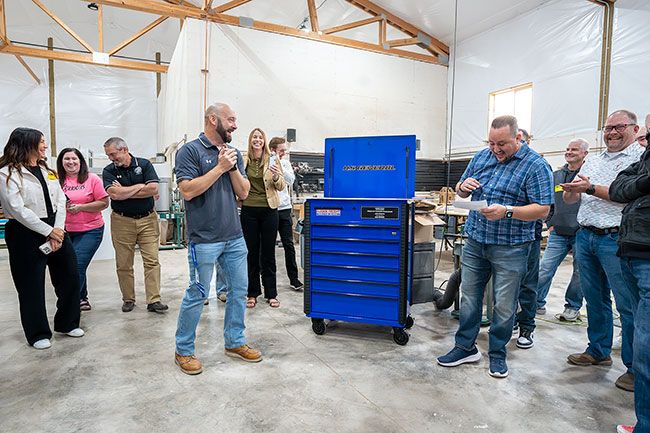 Rachel Thompson/News-Register##Surrounded by well-wishers from Amity High School, Harbor Freight employees and elected officials, John Stearns, center left, delights in winning a tool chest — an appropriate trophy for a construction teacher — as well as money for his school in the Harbor Freight Tools for Schools competition. Harbor Freight District Manager Dave Minch, center right, announced the honor at a surprise gathering Tuesday in the Amity High Career-Tech Education building.