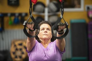 Rusty Rae/News-Register##Kerry Brownridge pulls herself up in an incline chest press during X-Camp class. She is among a crew of pre-dawn workout regulars at Excell Fitness in McMinnville between 6 and 7 a.m.