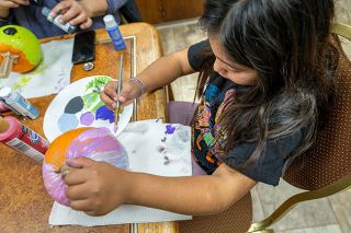 Rusty Rae/News-Register##Anastasia Martinez, 7, of McMinnville focuses her creative efforts on painting a pumpkin on Oct. 25 at Provoking Hope. The nonprofit will give away treats on Halloween afternoon, 2:30 p.m. to 4:30 p.m., at 239 N.E. Eighth St.