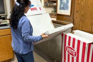 Kirby Neumann-Rea/News-Register##Clerk’s office employee Suzie Sutton dismantles one of three cardboard voting booths Tuesday around 9 p.m., in the lobby of the Evans Street building. Sutton lovingly refers to the “Votabooth” as resembling a pizza box and popcorn container. The booths are used extensively during election season by people who fill out their ballots on site, Clerk Keri Hinton said. The 1970s-era Votabooths still contain instructions from pre-vote-by-mail days: “You may not remove ballot from the polling place,” they reads. Voters would fill in the center part of an arrow next to each ballot choice, and hand the ballot to a ballot clerk who would tear off a ballot stub as proof of voting.