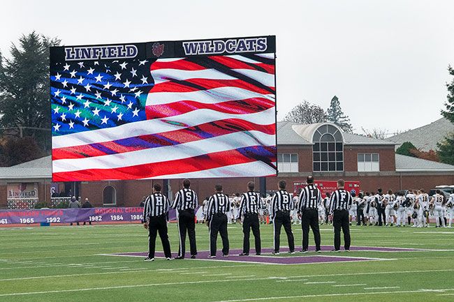 Rusty Rae/News-Register##
Members of the officiating team from Saturday’s Linfield-Pacific Lutheran contest salute the flag on Maxwell Field’s giant video board during the Star Spangled Banner, part of a Veterans Day tribute prior to the game, won by Linfield. Veterans Day observances at the game included armed services anthems by the Linfield band played at halftime.