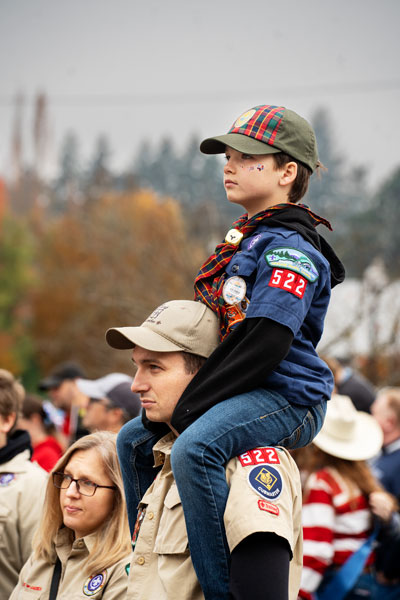 Rachel Thompson/News-Register##Cubmaster Kevin Wherry gives scout Eli Wherry, 10, a boost so he can see everything in the parade. Marie Wherry is at left. Troop 522 and other scout troops turned out for the event, along with the Navy Sea Cadets, cheerleaders and members of other organizations wanting to honor veterans, police officers, firefighters and other first responders.