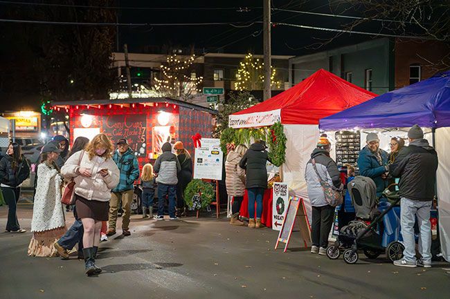 Rachel Thompson/News-Register##Revelers visit lighted booths at the Glide and Gather Holiday Market, which features several local vendors offering wreaths, gift items, food and beverages, including hot cocoa. Although the ice skating rink had not yet been assembled for use, the market was open for business over the weekend. Chamber of Commerce officials said the market and the rink will be open from 4 to 8 p.m. Fridays, noon to 6 p.m. Saturdays and noon to 4 p.m. Sundays through Dec. 22 on the Oregon Mutual parking lot at Fourth and Baker streets.