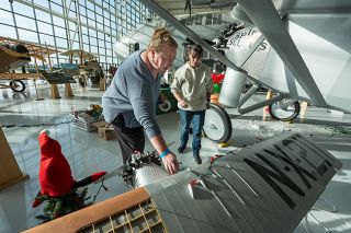 Rachel Thompson/News-Register##Chemeketa Community College’s Renae White, left, adjusts lights on the miniature Spirit of St. Louis that sits under the wing of a replica of the real plane. She and Brandy Lehn, center, were decorating both the small and large planes for Goose Lights, the holiday light show at the Evergreen Aviation Museum. Chemeketa’s Yamhill Valley Campus was among several organizations and businesses participating in Goose Lights, which will be open to the public from 5 to 7 p.m. daily, Dec. 14 to 21. Ticket sales benefit the Yamhill County Food Bank.