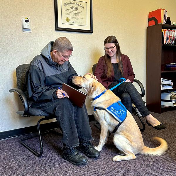 Rachel Thompson/News-Register##News-Register reporter Paul Daquilante gets to know the new courthouse dog, Nacho, in this photo taken on March 3, 2023, as he interviews Sarah Grabner, right, Crime Victim Services Supervisor for the Yamhill County District Attorney’s Office. The article, “Caring canine: Nacho settles into work as new county courthouse facility dog” appeared in the March 21 edition.