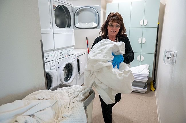 Rusty Rae/News-Register##YCAP employee Dolley Mack takes bedding from a dryer at AnyDoor Place navigation center. The 36-bed facility is regularly cleaned between client stays.