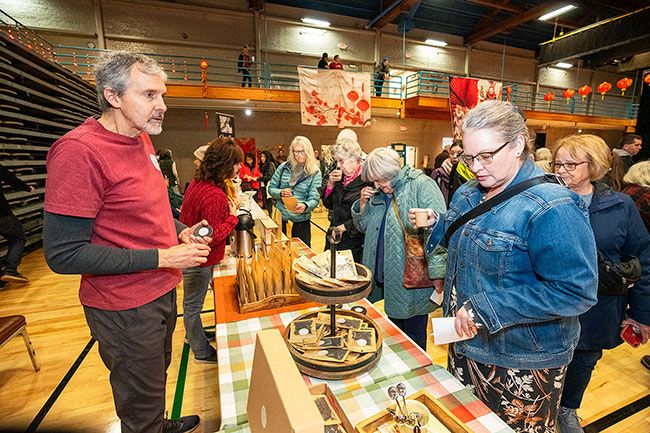 Rachel Thompson/News-Register##Brad Landsiedel of Tea Musketeers of McMinnville shares samples of China Rose and Dragon Oolong teas with customer Angelene Green, from Corvallis, right. Brad’s wife, Patty, is in the background. The Landsiedels started the business in 2020. They have 36 teas for sale on their website, teamusketeers.com, and can also be found locally at NW Food and Gifts, Nash & Nichol and Blue Raeven Farmstand.