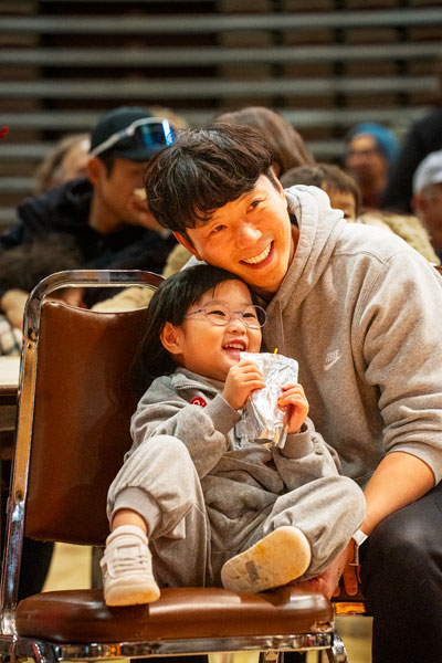 Rachel Thompson/News-Register##Jiwoo Kim, age 3, with her father, Jun Kim of Hillsboro, watch the dance presentations by Oregon Korean Performing Arts. Jun, born in Korea, moved to the United States as a child. “It was amazing. She really enjoyed it. We don’t get to see those things very often,” Jun said.