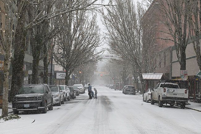 Rusty Rae/News-Register##Pedestrians carefully cross Third Street during a snowstorm Thursday morning. Snow piled up on streets and fields across Yamhill County as temperatures remained below freezing Thursday and overnight. Forecasters say snow will gradually give way to rain as temperatures warm Friday afternoon and over the weekend.