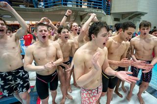 Rachel Thompson/News-Register##The McMinnville boys swimming team cheers as they approach the podium at last Saturday’s Pacific Conference Districts meet, celebrating the team’s dominant first-place performance.