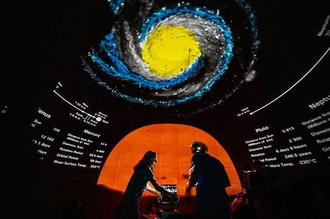 Rachel Thompson/News-Register##“Mercury: mean surface temperature 350 degrees”: planetarium Caitlin Hudson and Roger Pence are surrounded by solar system images and information.