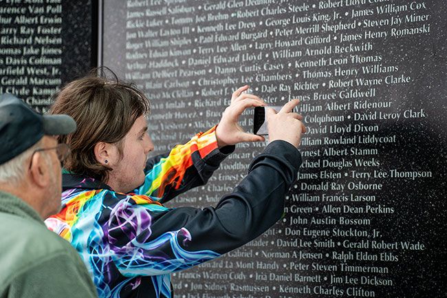 Rachel Thompson/News-Register##Vietnam veteran Jack Fidler of Amity, watches his grandson, Truxton Myers of Amity, take a photo of William Albert Ridenour’s name on the commemorative wall. Ridenour was a friend and next door neighbor of Fidler. They visited also to see the name of Joseph Allen Jeffries, Jack Fidler’s son-in-law, who died in Iraq. Rachel Thompson/News-Register##Vietnam veteran Jack Fidler of Amity, watches his grandson, Truxton Myers of Amity, take a photo of William Albert Ridenour’s name on the commemorative wall. Ridenour was a friend and next door neighbor of Fidler. They visited also to see the name of Joseph Allen Jeffries, Jack Fidler’s son-in-law, who died in Iraq.