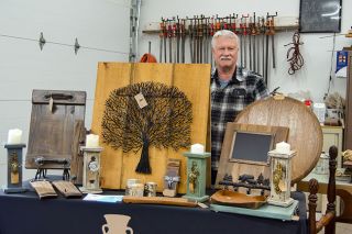 Rachel Thompson/News-Register##Bill Willis, a longtime woodworker, stands with a display of some of the pieces available at Earth & Wood, the Amity shop he runs with his son, Dan Willis. The elder Willis created the wood items, with a collaborator providing the metal tree. Rachel Thompson/News-Register##Bill Willis, a longtime woodworker, stands with a display of some of the pieces available at Earth & Wood, the Amity shop he runs with his son, Dan Willis. The elder Willis created the wood items, with a collaborator providing the metal tree.