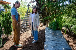Rachel Thompson/News-Register##Abraham and Sara Hanson admire the golden cedar slab bench he crafted from a tree felled in their yard — one of many family-friendly garden features visitors will see during the McMinnville Garden Tour on Sunday, June 8. A wooden tepee in the background, constructed during a socially distanced birthday party, now stands as a playful garden relic. Rachel Thompson/News-Register##Abraham and Sara Hanson admire the golden cedar slab bench he crafted from a tree felled in their yard — one of many family-friendly garden features visitors will see during the McMinnville Garden Tour on Sunday, June 8. A wooden tepee in the background, constructed during a socially distanced birthday party, now stands as a playful garden relic.