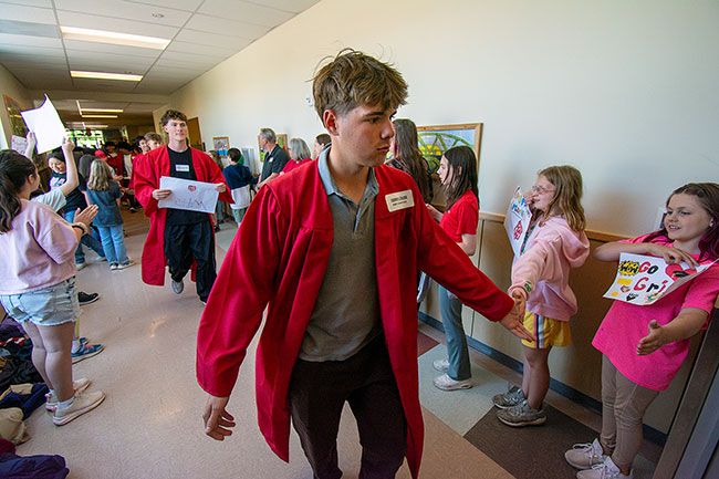 Rachel Thompson/News-Register##On the day before graduation, McMinnville High School senior Tanner Leikam high-fives fourth-grader Olivia Libonati during the annual parade of graduates at Newby Elementary School. He’s joined by fellow senior Metolius Halloran-Steiner and 75 classmates. Newby students lined the halls, waving handmade signs and cheering, “Let’s go Grizzlies!” and “Grizz-LIES! Grizz-LIES!” In a tradition that began in 2013, Mac High seniors visit their former elementary schools to inspire younger students to look ahead to their own graduations. Rachel Thompson/News-Register##On the day before graduation, McMinnville High School senior Tanner Leikam high-fives fourth-grader Olivia Libonati during the annual parade of graduates at Newby Elementary School. He’s joined by fellow senior Metolius Halloran-Steiner and 75 classmates. Newby students lined the halls, waving handmade signs and cheering, “Let’s go Grizzlies!” and “Grizz-LIES! Grizz-LIES!” In a tradition that began in 2013, Mac High seniors visit their former elementary schools to inspire younger students to look ahead to their own graduations.