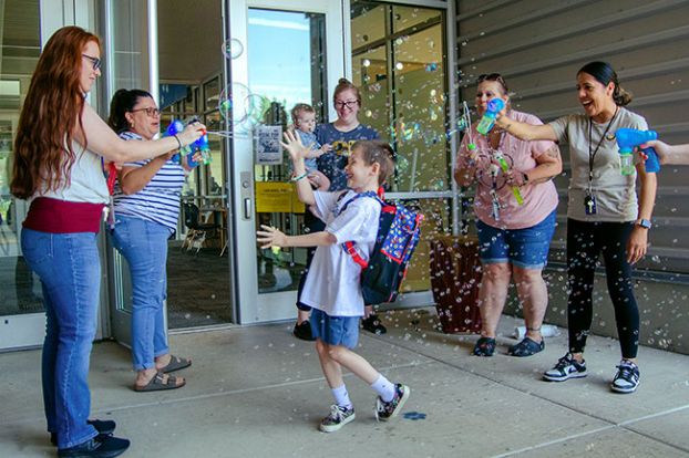 Rachel Thompson/News-Register##Owyn Bennett spins around in excitement as he leaves Buel Elementary School on his last day of first grade. With him are his mom, Kelsey, holding little brother Wali, and staff members blowing bubbles — from left, Koreena Petschauer, Laura Rivas, Kara Ecker and Emma Velazquez. Owyn said he’s excited about making art this summer and becoming a second-grader in the fall.
