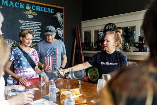 Rachel Thompson/News-Register##Erin Bowman, owner of Mack & Cheese, pours wine and serves Milton cheddar to Renee and Steve Norman during Taste of Mac 2025 on Saturday in downtown McMinnville. The annual event invites visitors to sample bites, drinks and treats from 37 local wineries, breweries, eateries and shops along Third Street, with proceeds benefiting McMinnville Oregon Lions Club charities.