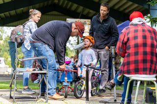 Rachel Thompson/News-Register##Brian Prevett installs a new bike bell for Lillian Monroe, 3, as her parents look on during the bike rodeo at Hometown Days on Friday. Prevett helped young riders with quick fixes and tune-ups throughout the afternoon. Rachel Thompson/News-Register##Brian Prevett installs a new bike bell for Lillian Monroe, 3, as her parents look on during the bike rodeo at Hometown Days on Friday. Prevett helped young riders with quick fixes and tune-ups throughout the afternoon.