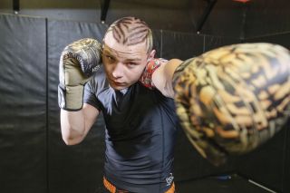 Devin Huston, with boxing gloves matching his eccentric ever-changing hair style, poses for a photo inside of the WHS wrestling room after a wrestling practice. 
Rusty Rae/News-Register