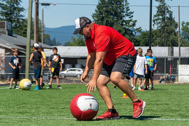 Nathan Ecker/The News-Register##Matson shows off a figure eight weighted ball drill where participants are instructed to stay low to the ground while pushing the ball in front of them. This drill, and others like it, were put together from various inspirations so that kids can learn about injury prevention, functional strength, quick twitch muscles, agility and physical fitness.