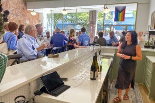 Starla Pointer/News-Register##Celestial Hill winemaker Alisa Le works behind the bar at the winery’s new tasting room, pouring for visitors including Nick Peirano during a grand opening Wednesday. Other business owners, wine club members and city and Chamber officials attended the event hosted by Celestial Hill owners Chris and Melissa Thomas. The space previously held Peirano & Daughter, a deli shop, and is next to Nick Peirano’s former cafe.