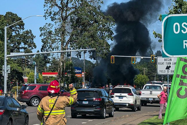 Ossie Bladine/News-Register##A McMinnville firefighter tells an onlooker to move back Tuesday as emergency personnel began to evacuate the area surrounding a car and propane tank fire near the intersection of Highway 99W and Lafayette Avenue. In the background, a McMinnville police officer directs traffic onto Lafayette Avenue. Ossie Bladine/News-Register##A McMinnville firefighter tells an onlooker to move back Tuesday as emergency personnel began to evacuate the area surrounding a car and propane tank fire near the intersection of Highway 99W and Lafayette Avenue. In the background, a McMinnville police officer directs traffic onto Lafayette Avenue.