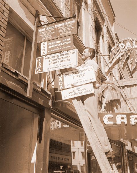 (July 26, 1955) ##Ed Laird, conservationist, is shown putting up a sign pointing out the new location of the Soil Conservation Service office. The office, one block east of its former location, is in the Union Building. The new location will mean added convenience for farmers, who will be able to transact all their business with regard to a particular conservation project in one building. (July 26, 1955) ##Ed Laird, conservationist, is shown putting up a sign pointing out the new location of the Soil Conservation Service office. The office, one block east of its former location, is in the Union Building. The new location will mean added convenience for farmers, who will be able to transact all their business with regard to a particular conservation project in one building.