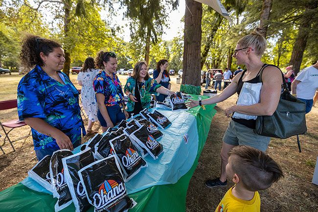 Rachel Thompson/News-Register## From left, Kaela Worden, Hannah Worden, Kari Worden and Julie Brandao hand out free T-shirts. Jennifer Schmidt and her son, Micah Klevens, 4, of Carlton, pick up shirts printed with the event&rsquo;s &ldquo;Ohana: CPD & Community Together&rdquo; graphic