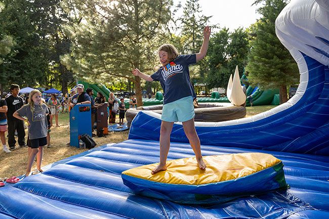 Rachel Thompson/News-Register##Paisley Dimick, 8, of Carlton tries her hand at the surfing machine during the National Night Out celebration, themed &ldquo;A Magical Tropical Island Evening.&rdquo;