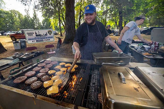 Rachel Thompson/News-Register##Sous chef Connor Patton of the Blind Pig in Carlton flips burgers alongside Line Cook Brody Quick. Volunteers staffed the grill and all other booths at the free evening of food, music and community connection.