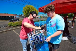 Rachel Thompson/The News-Register##Stefanie Riddle pours donated containers into a bag held by her son, Henry, during a Grad Night Class of 2026 can and bottle collection event on Saturday, July 5. The high school PTA has collection events every first Saturday of the month. Rachel Thompson/The News-Register##Stefanie Riddle pours donated containers into a bag held by her son, Henry, during a Grad Night Class of 2026 can and bottle collection event on Saturday, July 5. The high school PTA has collection events every first Saturday of the month.