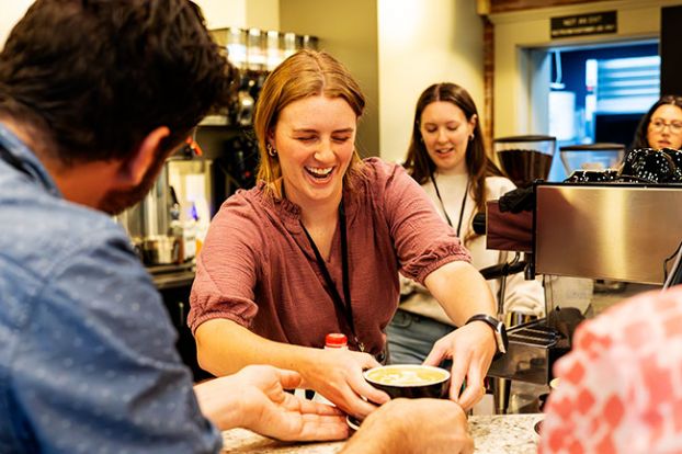 Rachel Thompson/News-Register##Anna Anderson sets her finished latte art creation onto the counter in front of judge Eric Berg. Behind her is her competitor, Rosie Porter. Sixteen baristas, with a wide range of experience, competed in the Latte Art Throwdown at Union Block Coffee in McMinnville Thursday. About 50 people cheered them on.