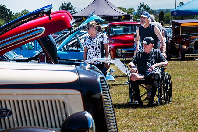 Rusty Rae/News-Register##Dina Diaz, a caretaker with Adult Foster Care in Grand Ronde, checks one of several intake trucks at the Rock of Ages Car Show Saturday. Looking on are Larry Cole in the chair and Butch Soderberg, both residents at AFC.
