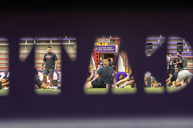 Nathan Ecker/News-Register##Linfield football players receive instruction from assistant coach Nicholas Kernaghan on the first day of practice. Players hustled all around the athletic facilities as the morning clouds broke apart to reveal sunshine soon after practice began. Players and coaches in the photo are framed by the &ldquo;Catdome&rdquo; lettering plastered around Maxwell Field and on the sideline benches.
