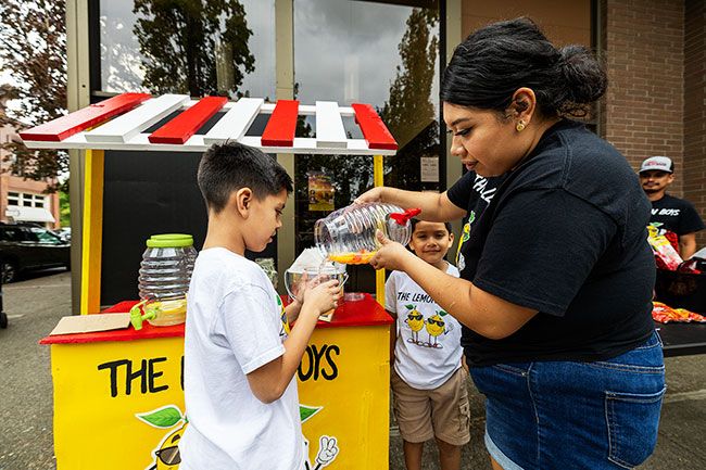 Rachel Thompson/News-Register##Ruby Lopez helps her son Manny Lopez-Victoria, 9, empty the last of his strawberry lemonade into a cup at The Lemon Boys stand, while his brother Damian, 8, and Juan Lopez look on. Manny, a Lemonade Day veteran since age 5, added peach to his recipes this year and quickly sold out. Rachel Thompson/News-Register##Ruby Lopez helps her son Manny Lopez-Victoria, 9, empty the last of his strawberry lemonade into a cup at The Lemon Boys stand, while his brother Damian, 8, and Juan Lopez look on. Manny, a Lemonade Day veteran since age 5, added peach to his recipes this year and quickly sold out.