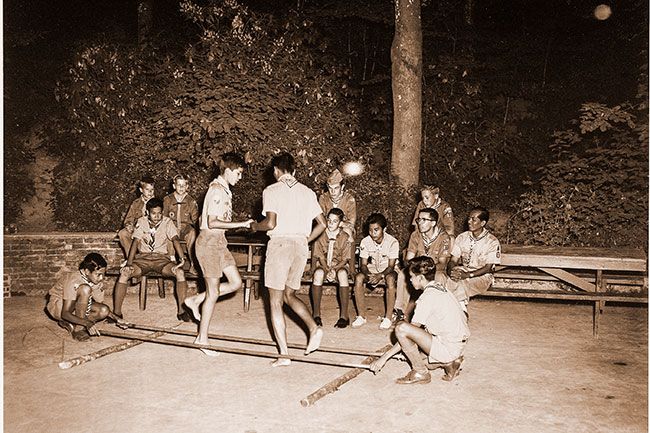 ##(Aug. 23, 1960) Six Philippine Islands Boy Scouts Thursday night presented a performance of “Tinikling” their national folk dance for McMinnville Scouts. Participants in the dance, left to right, are Tom Alcantara, Jorge Baccay, Gus Dacudas and Noli Fuentebella. Members of the audience were, seated left to right, front row, Eddie Echauz, Gary Gammon, Fred Arago, Ron Johnson, McMinnvilIe scoutmaster, and Jimmy Jarmang, Philippine scoutmaster, and seated back row, Scott Larsen, Bill Vinton, Tom Linderoth and Burt Nicoll. They performed at a picnic at the city park.