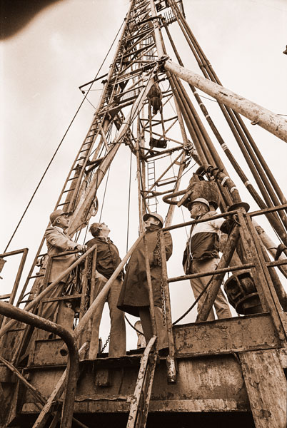 ##(Aug. 29, 1975) Standing on the base platform, company executives take a look at the natural gas well drilling rig lowering some 127 feet above them South of Amity off Highway 99W. Project is a joint venture between Northwest Natural Gas Co. and Reichhold Energy Corporation.