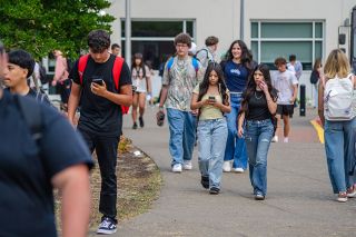 Rachel Thompson/News-Register##McMinnville High School students pull out their cell phones just after exiting the building at lunch time on Wednesday. New rules state phones must be put away all day, except for lunch; they cannot be used anywhere on campus, so students need to cross the street before dialing or texting — something staff members are reminding them as the school year gets underway.