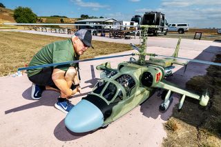 Rachel Thompson/News-Register##Gonzalo Martinez of the San Francisco area, who founded the Helicopter Scale Masters fly-in, looks over his rare Russian Kamov Ka-52 combat model. This is the first time the fly-in has been held outside Davis, California; it will return to McMinnville again in 2026, and an additional McMinnville Aircraft Modelers event will be held at the airfield on Masonville Road in October.