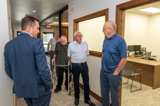 Rusty Rae/News-Register##Former Hagan Hamilton co-owner Skip Huwaldt, right, talks with another former co-owner Gordon Hall on his right and other former company leaders, including Neil Reiter, center, and Dale Moore, center right, at a preview of the remodeled building in which they once worked. Listening on the left is Jason John, who now runs the company with his brother, Brian John, since the 2021 retirement of their father, Rick John.