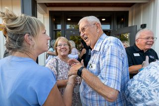 Rachel Thompson/News-Register##Joyce Kauer Mast, left, and her sister Janet Kauer Clow greet longtime MV Advancements board member Dave Haugeberg after the ribbon cutting at the nonprofit’s new headquarters. The sisters’ parents, Ray and Barbara Kauer, were instrumental in founding the organization in the 1960s to support their daughter Linda and other adults with disabilities.