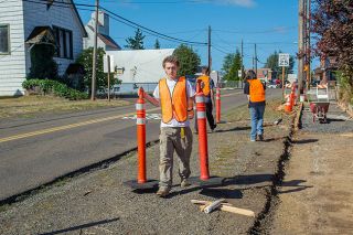 Emily Bonsant/News-Register##Wolfgang Tasa of McMinnville moves traffic cones during sidewalk construction on East Main Street in Carlton. Tasa is participating in construction workforce training with the Youth Opportunity Program, which partnered with the city of Carlton, SEDCOR and Willamette Workforce Partnership for the project. Other workforce trainees Harold Crow of Newberg and Emma Oglesby of McMinnville grab additional equipment as the crew helps install the sidewalk. The project will result in 822 feet of new sidewalk.