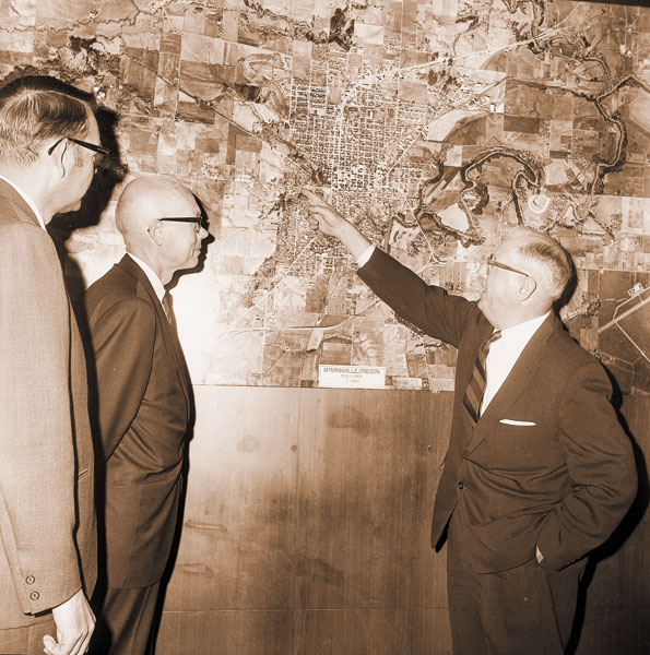 (Sept. 23, 1970) J. Haslett Bell, Portland landscape architect and planner, looks at map of city of McMinnville recently during visit with city officials and others interested in planning. At left is Joe Dancer, city manager, and Clarence Caughran, chairman of the Mayor’s Citizens Advisory Committee on Planning. Bell developed a master plan for the city over 20 years ago.