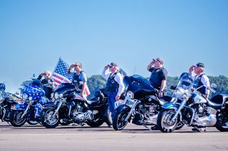 Rachel Thompson/News-Register##Members of the Legion Riders from McMinnville Post 21 salute during the National Anthem during opening ceremonies for the Oregon International Air Show on Friday. The Riders rode in with flags flying to start the event each day. The patriotic opening was accompanied by a flyover from the Oregon Air National Guard.