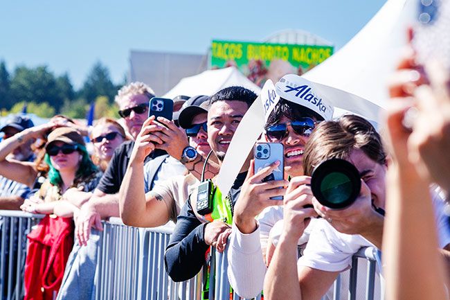 Rachel Thompson/News-Register##Spectators line the fence to capture the action overhead Friday during the Oregon International Air Show at McMinnville Municipal Airport. Sunny skies and roaring engines drew crowds for three days of aerial performances, vintage aircraft and military flyovers.