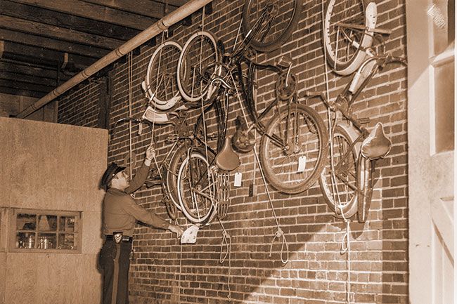 ##(Oct. 1, 1955) McMinnville city policeman, Herb Hale, hoists another bike into place in the police department bike “morgue.” Bicycles are either picked up after being abandoned, or have been impounded by police for violations on part of youthful bike jockeys.