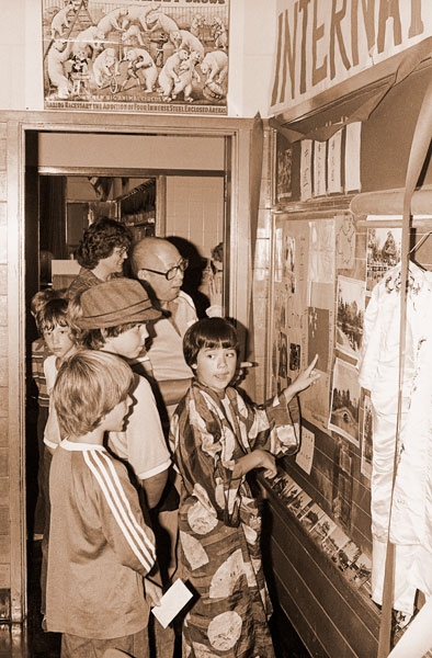 ## (Oct. 1, 1980) Mike Wong, a fifth grader at Memorial Grade School, shows classmates Jason Bertagna and Jack Forde some of the Chinese heirlooms of his family as his father, Frank, looks on. Youngsters in the classes of Connie Duncan and David Stairs presented a Heritage Day program at the school Monday in connection with their studies of immigration.