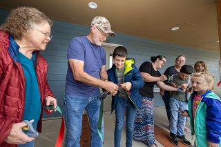 Rachel Thompson/News-Register##Abel Stadeli, 13, gets a little help from Dave Hakola as they cut a section of ribbon during Saturday’s grand opening of the Dayton Community Food Pantry and Clothes Closet. At left is Anita Hakola, and at right is Gisele Stadeli, 6. Also pictured are Susan Stadeli with her son Israel, 10, and Joni Diers with granddaughter Elyse Bunn, 10, in the background.