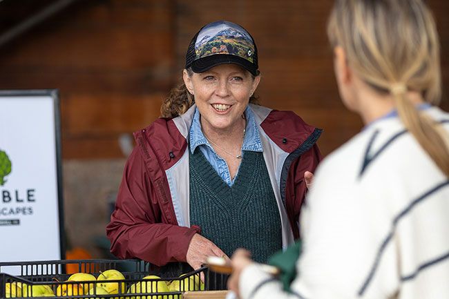 Rachel Thompson/News-Register##Patty Herzog, a board member of Edible Landscapes of Yamhill County, chats with visitors during Saturday’s Community Harvest Exchange at Mac Market in McMinnville. Community members gathered to celebrate the season, sharing surplus from their gardens and enjoying fresh-pressed cider. All unclaimed produce was donated to the YCAP food bank. Rachel Thompson/News-Register##Patty Herzog, a board member of Edible Landscapes of Yamhill County, chats with visitors during Saturday’s Community Harvest Exchange at Mac Market in McMinnville. Community members gathered to celebrate the season, sharing surplus from their gardens and enjoying fresh-pressed cider. All unclaimed produce was donated to the YCAP food bank.