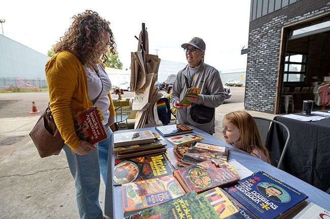 Rachel Thompson/News-Register##eigha Hill, left, and her daughter Vivienne, 5, of McMinnville browse free gardening and cookbooks with Joyce Anderson of Friends of the McMinnville Public Library during the event at Mac Market. Rachel Thompson/News-Register##eigha Hill, left, and her daughter Vivienne, 5, of McMinnville browse free gardening and cookbooks with Joyce Anderson of Friends of the McMinnville Public Library during the event at Mac Market.